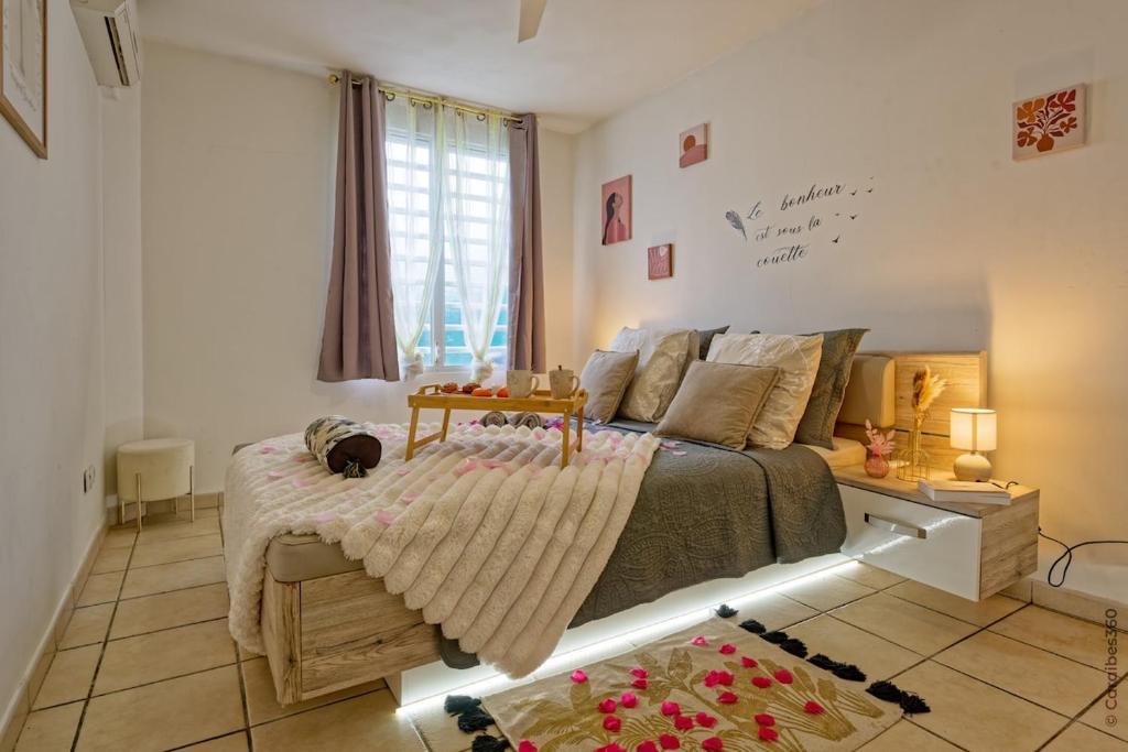 a bedroom with a bed with a table on it at Nid rose paradis secret au robert avec jacuzzi in Le Robert