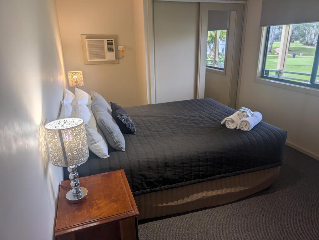 a bedroom with a bed and a lamp and a window at Riverside Golf Club in Gol Gol
