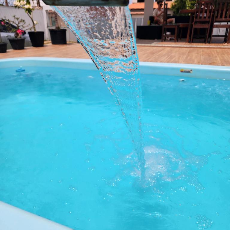 a water fountain spraying water into a swimming pool at Casa em São Mateus - Guriri in São Mateus