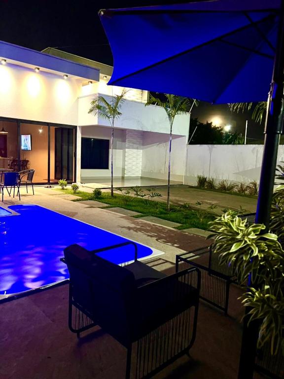 a swimming pool at night with a large blue umbrella at casa com piscina in Sinop