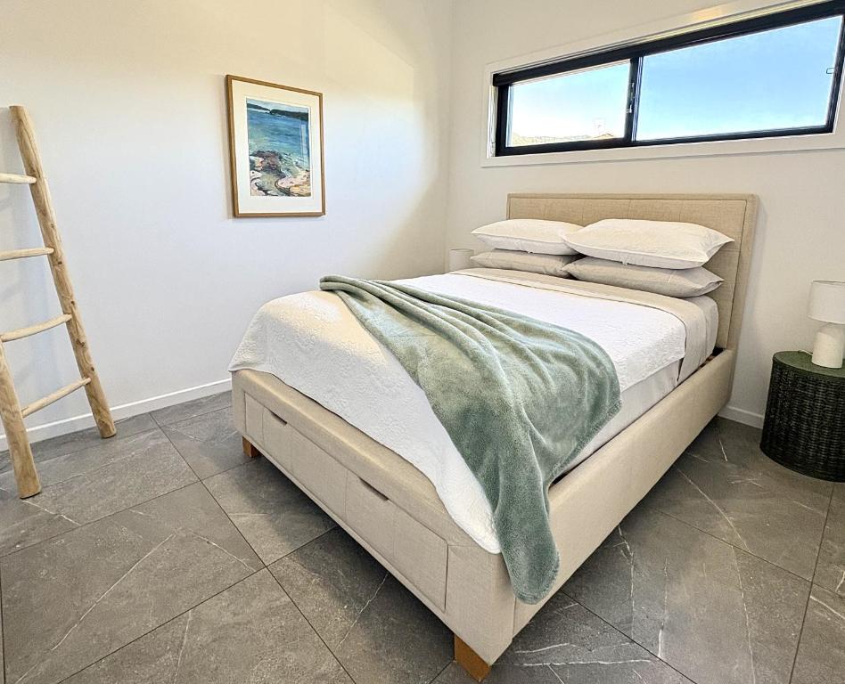 a bedroom with a bed with a green blanket on it at Korora's Haven Coffs Harbour in Kororo Basin