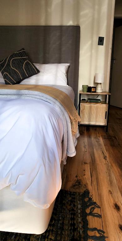 a bedroom with a white bed and a wooden floor at Modern retro private apartment in Polokwane