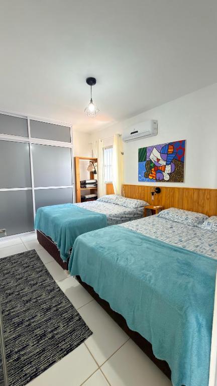 two beds in a hotel room with blue sheets at Miau de Pipa in Pipa
