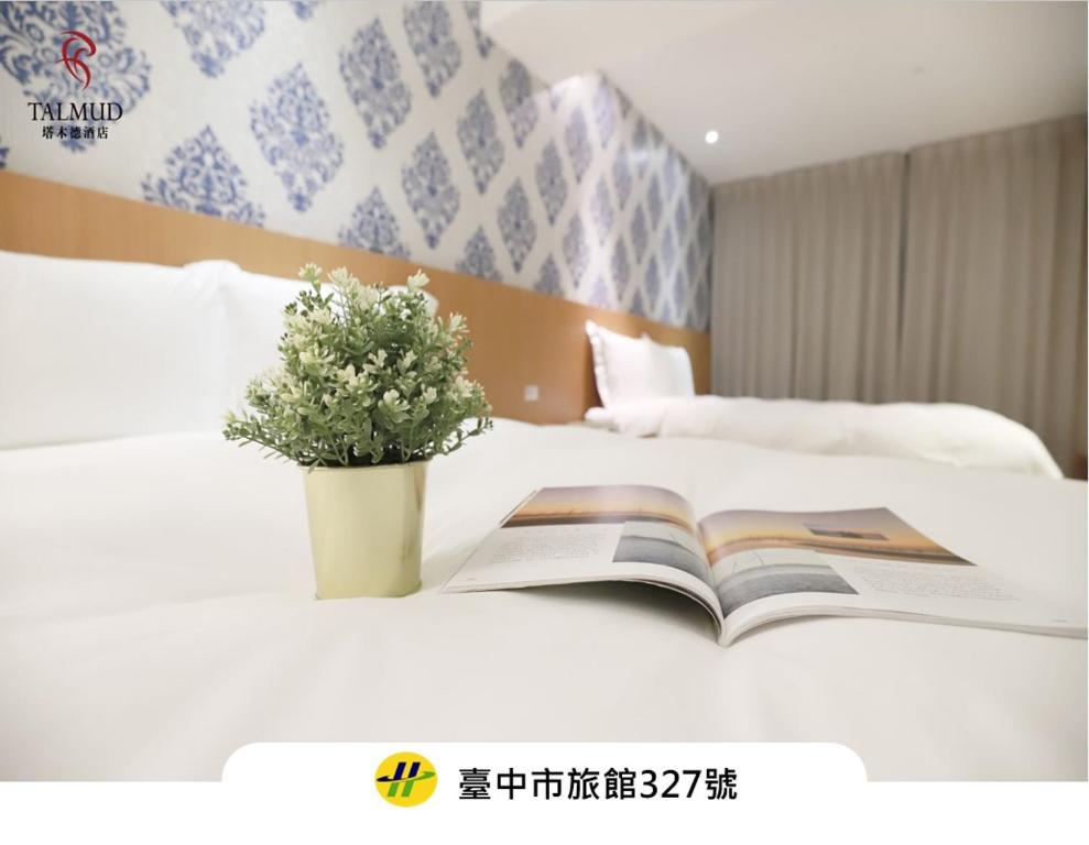a book on a bed with a plant on it at Talmud Hotel Yizhong in Taichung