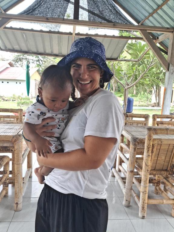 a woman holding a baby in her arms at Dinoyin Bungalows in Gili Meno