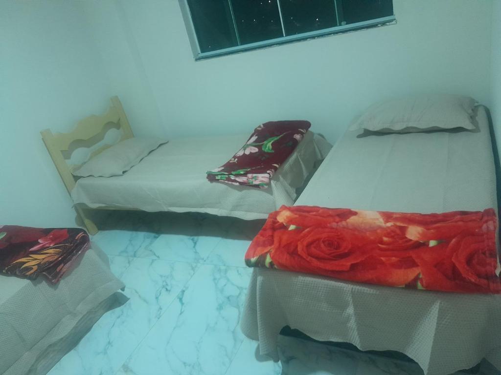 a room with three beds with a red rose on them at Guimarães in Viçosa