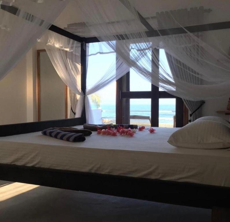 a bedroom with a bed with a view of the ocean at Cili Hotel & Pizza Restaurant in Arugam Bay