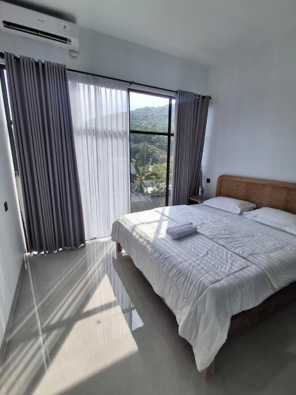 a bedroom with a bed and a large window at Poshaka Karimunjawa in Karimunjawa