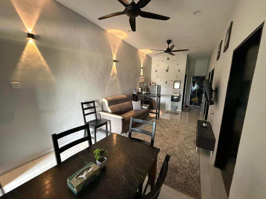 a living room with a table and a ceiling fan at Aden's Stopover House in Kuala Nerang