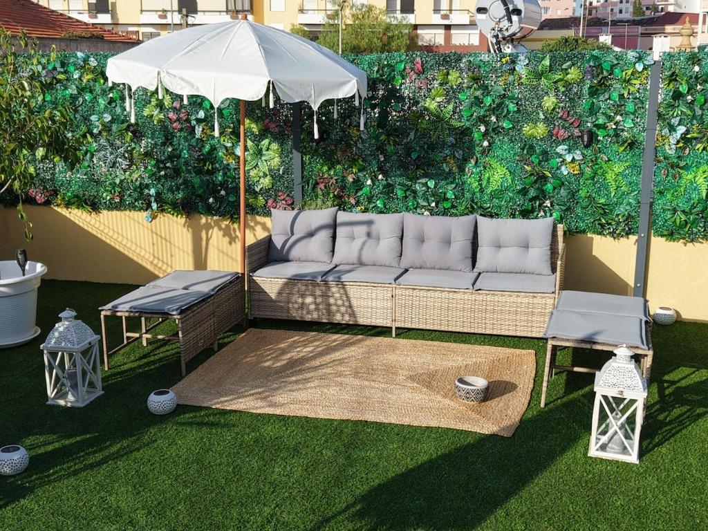 a couch sitting under an umbrella in a garden at Zen Terrace Townhouse in Faro