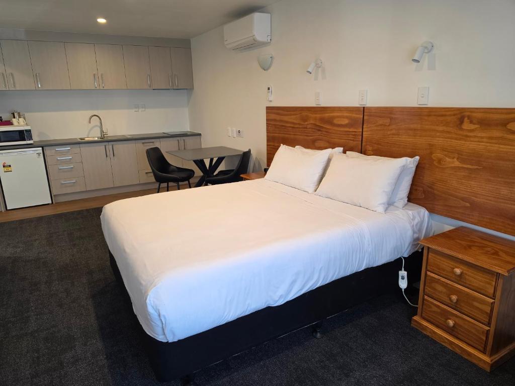 a bedroom with a large bed and a kitchen at Waikato Hospital Motel in Hamilton