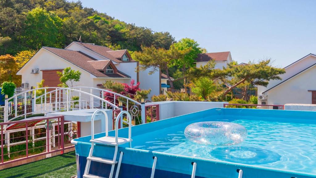 a blue pool with a chair in a yard with houses at Daebu-do, White Island Pension in Ansan