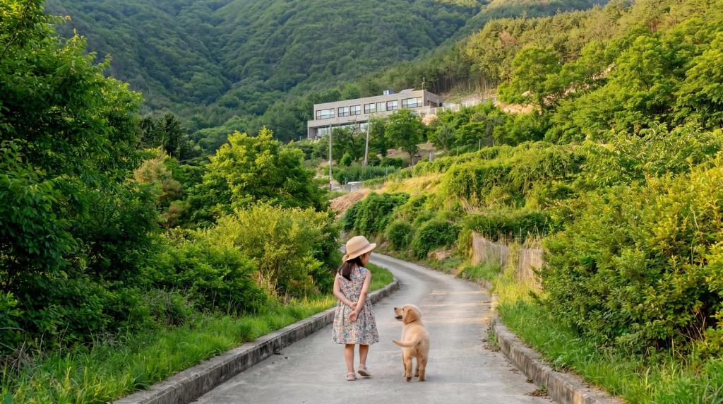 a woman walking a dog down a road at Sara&Forest Pension Mungyeong in Mungyeong