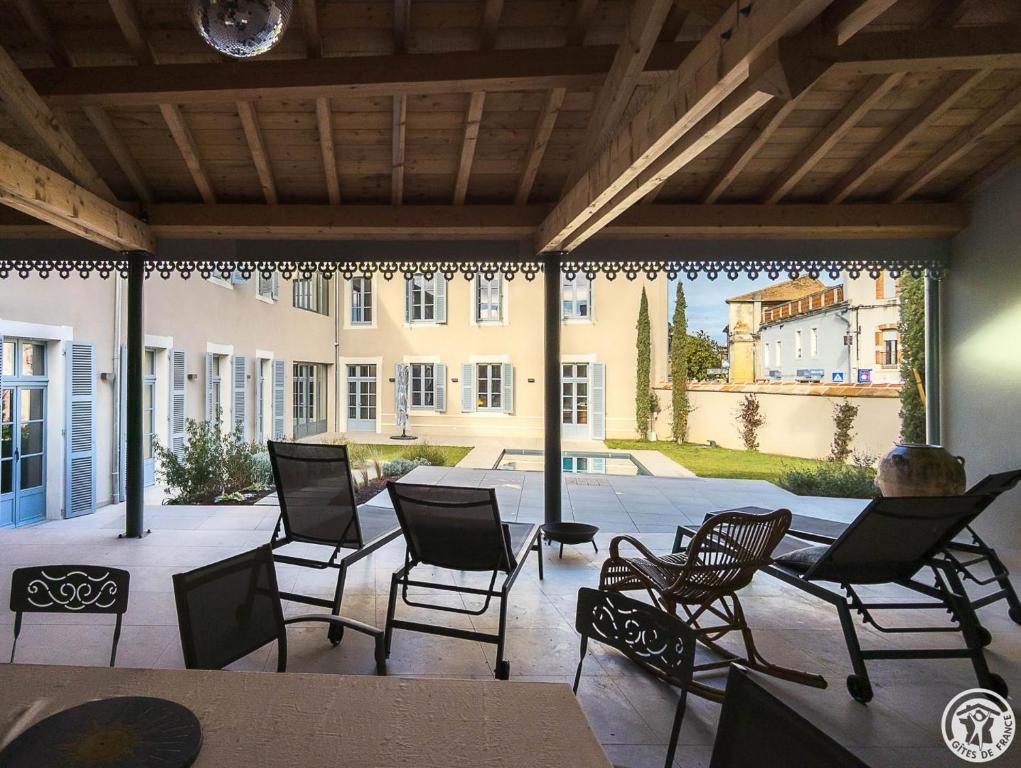 a patio with chairs and a table and a building at La villa saviesa in Cazères