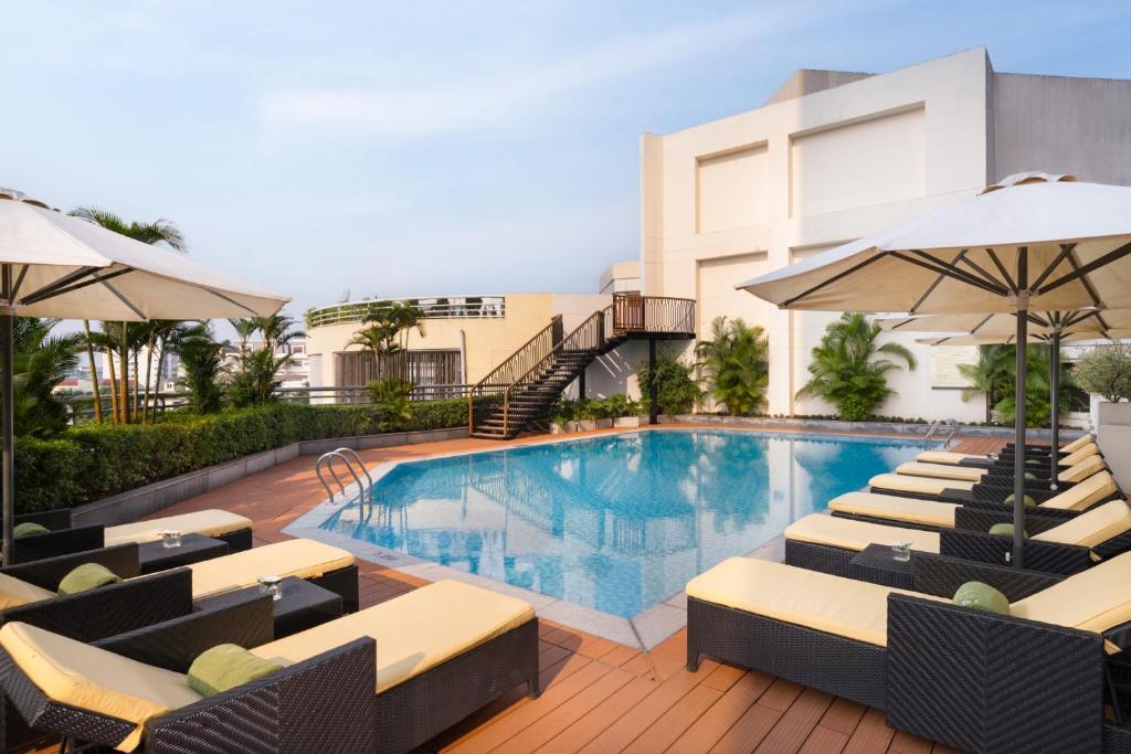 a pool at a hotel with chairs and umbrellas at Meliá Hanoi in Hanoi