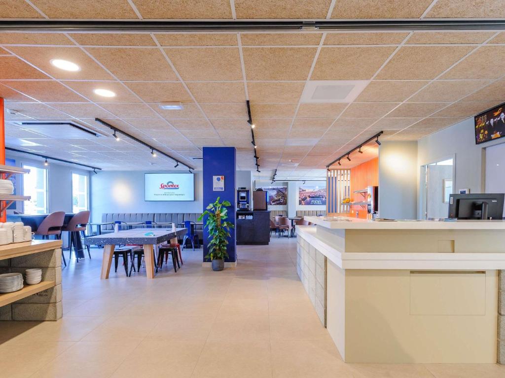a lobby of a restaurant with tables and chairs at Ibis Budget La Rochelle Puilboreau in Puilboreau