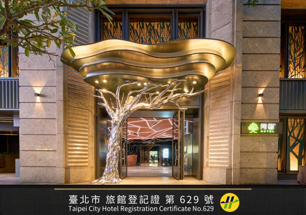 a large gold tree sculpture in front of a building at arTree hotel in Taipei