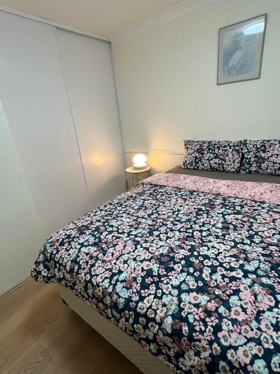 a bedroom with a bed with a floral bedspread at Private Rm4-Queen bed in Elderslie