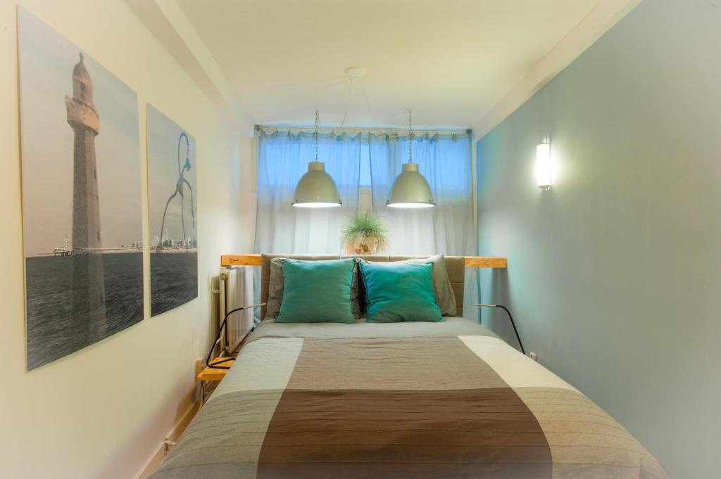 ein Schlafzimmer mit einem großen Bett mit blauen Kissen in der Unterkunft Bluebeach Scheveningen in Scheveningen