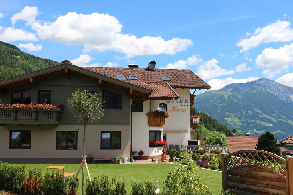 a house with a green yard and mountains in the background at Gästehaus Hanser in Virgen