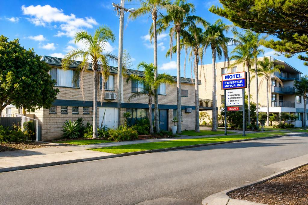 a street in front of a hotel with palm trees at Forster Motor Inn in Forster