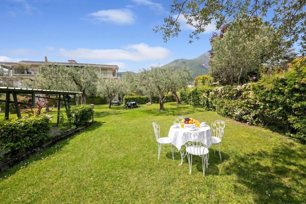 a table with white chairs in a yard at Margherita near lake - Family Friendly - Happy Rentals in Toscolano Maderno