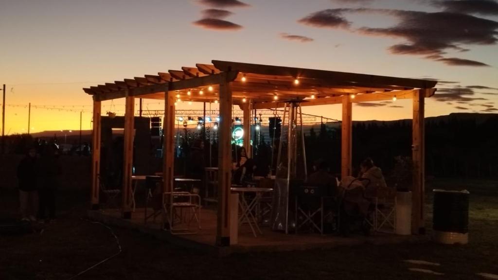 a pavilion with people sitting under it at sunset at Alojamiento Amado in Los Antiguos