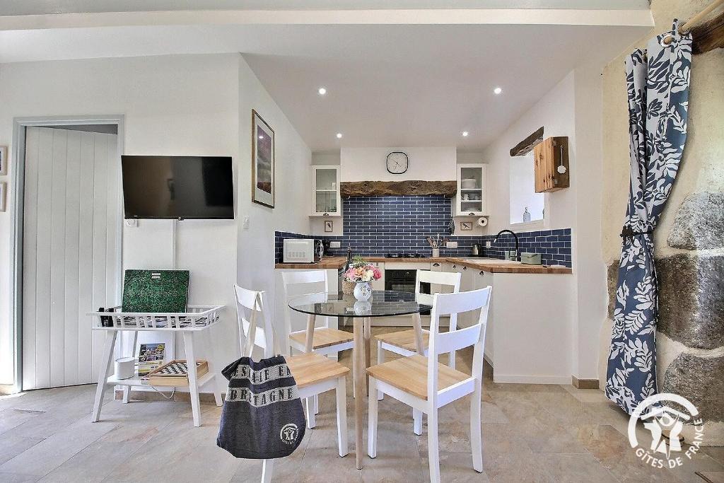 a kitchen and dining room with a table and chairs at Le murmure des oiseaux in Plussulien