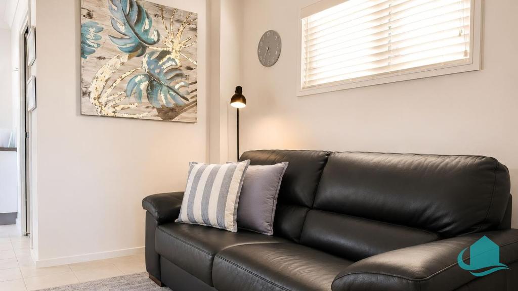a black leather couch in a living room with a lamp at Coastal Hideaway at Pelican in Pelican Flat