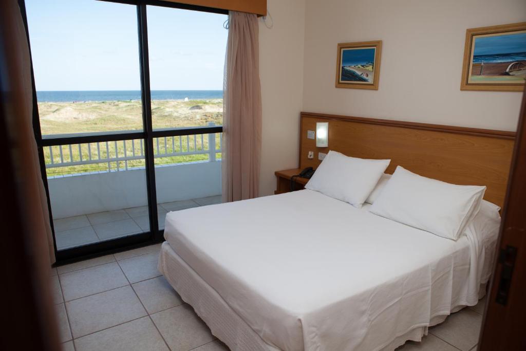 a bedroom with a bed and a view of the ocean at Nelson Praia Hotel in Cassino