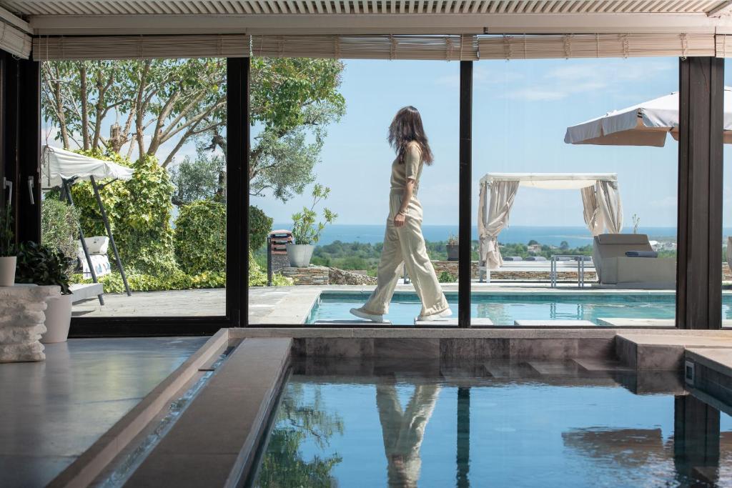 a woman walking by a pool in a house at Luxury Villa Christina in Makrygialos