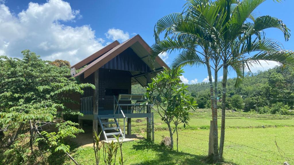 a tree house with a balcony and a palm tree at Poopha home stay in Amphoe Pai