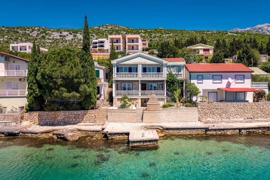 a large house sitting on top of a body of water at Seafront Escape - 4BR Beachfront Villa for 8 in Šibuljina