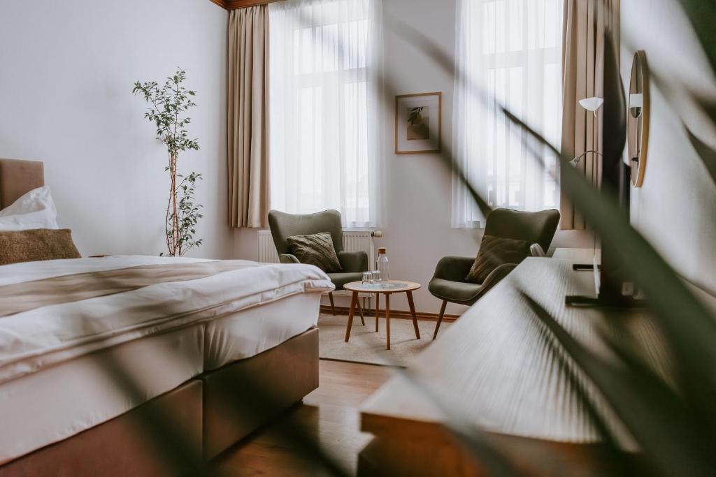 a hotel room with a bed and two chairs at Penzion Pod Kašnou in Frýdek-Místek