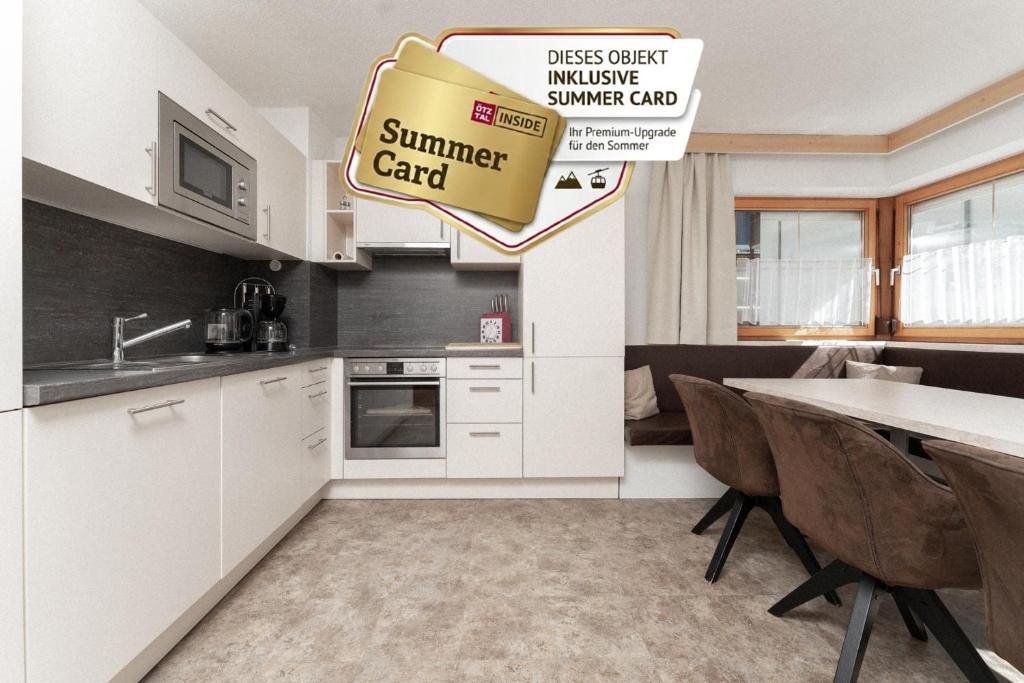a kitchen with white cabinets and a table with chairs at Appartement Gehörde-Sölden inklusive Summercard in Sölden