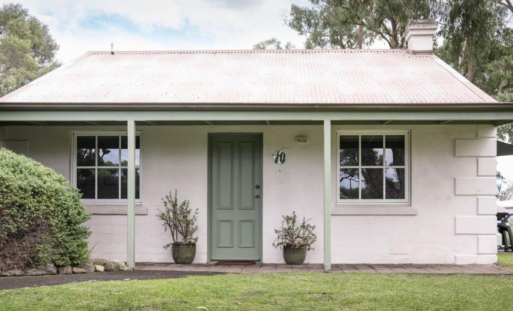 a small white house with a green door at Whalers Cottage in Port Fairy