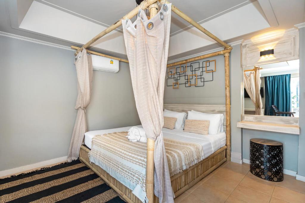 a bedroom with a canopy bed and a mirror at The Taksim Bangla Beach Hotel in Patong Beach