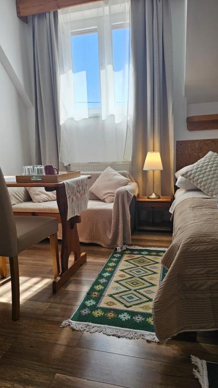 a bedroom with a bed and a desk and a window at Oberża Pod Kudłatym Aniołem in Cisna