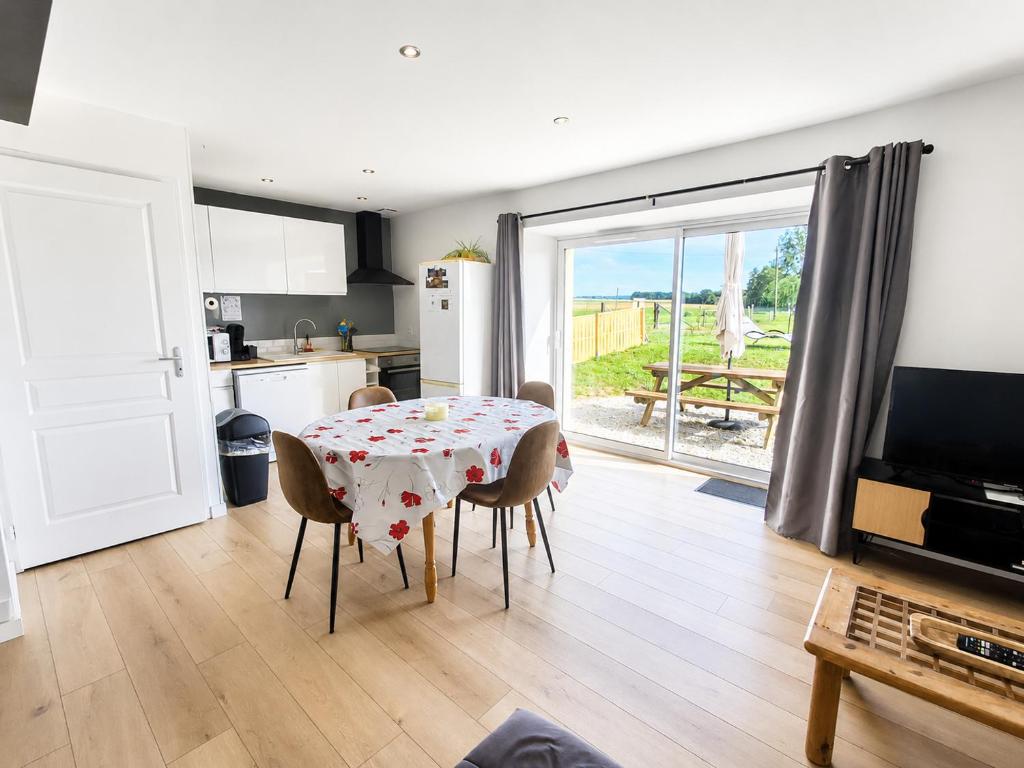 a kitchen and dining room with a table and chairs at Les Ch'tis Normands Gîte à la campagne avec terrain de pétanque in Mortrée