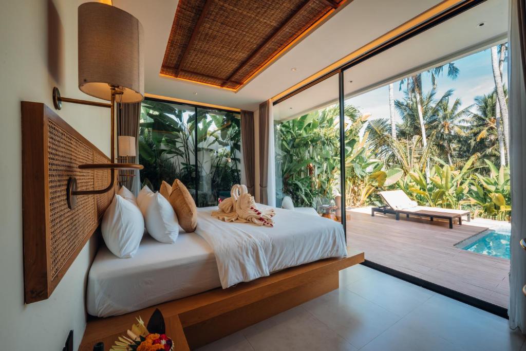a bedroom with a bed and a balcony with a pool at Candidasa Hills in Candidasa