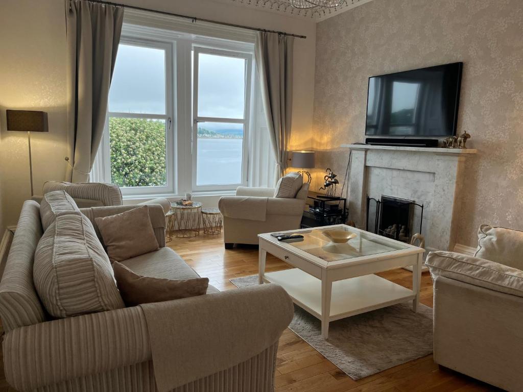 a living room with a couch and a tv and a fireplace at Harbour View - Waterfront Retreat, Rothesay in Rothesay
