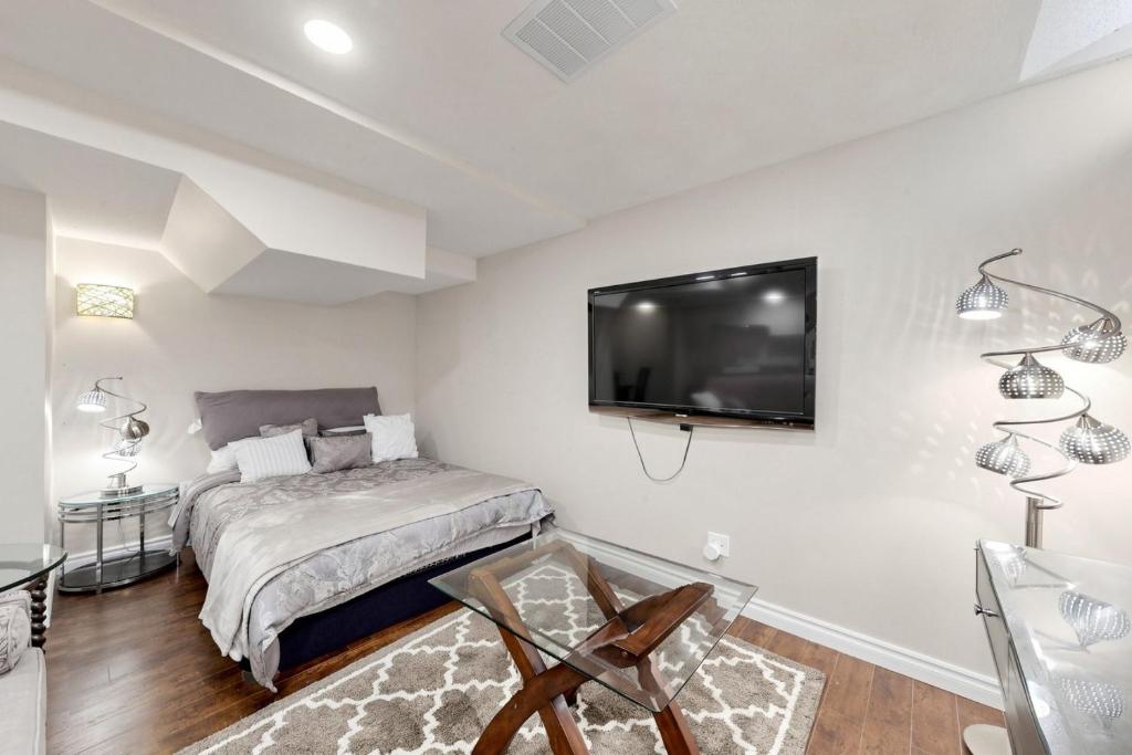 a bedroom with a bed and a tv on the wall at The Boxwood Executive Suite in Markham