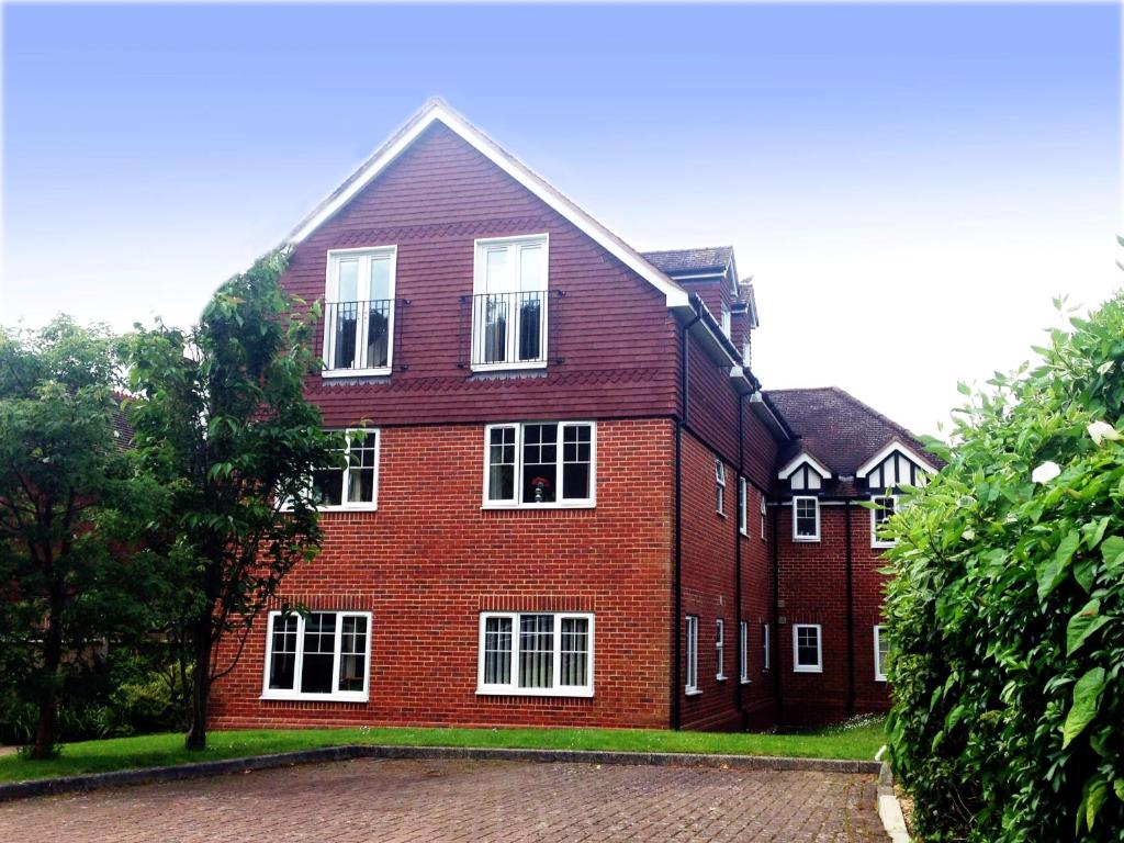 a large red brick building with white windows at St Raphael House, City Centre Charming Apartments in Basingstoke