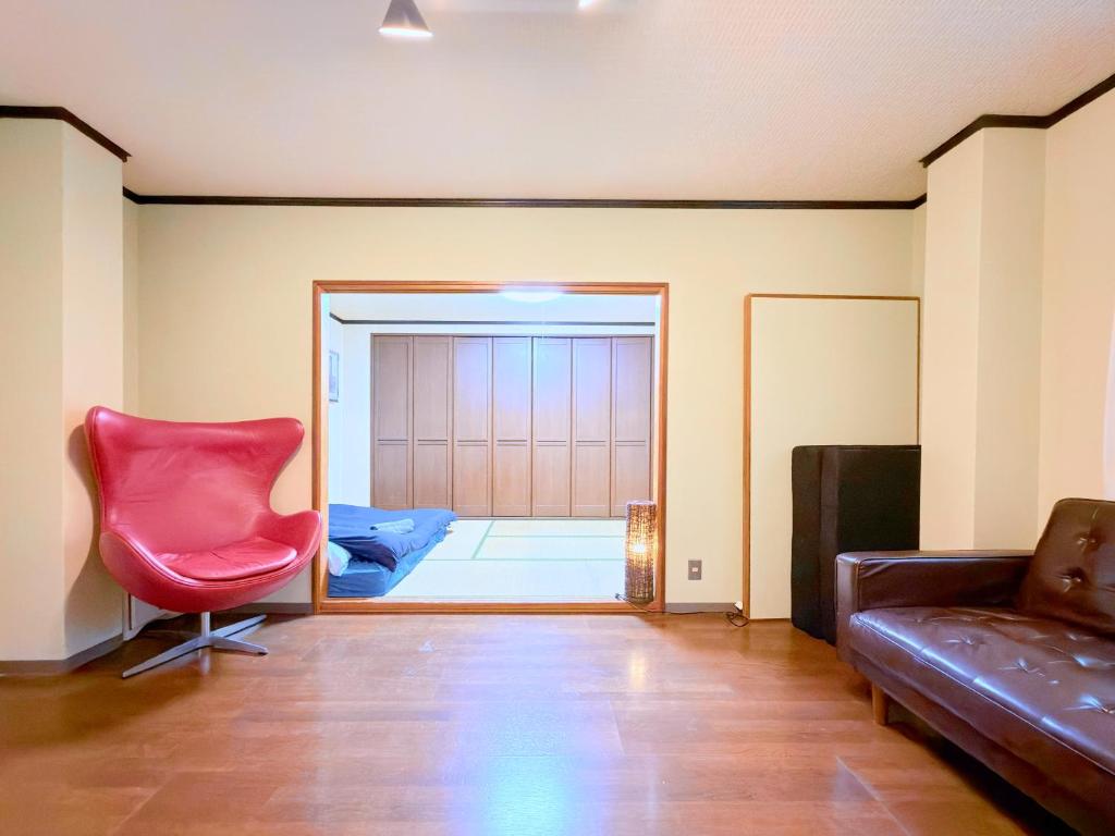 a living room with a red chair and a couch at NEXTRAVELER iNN in Osaka