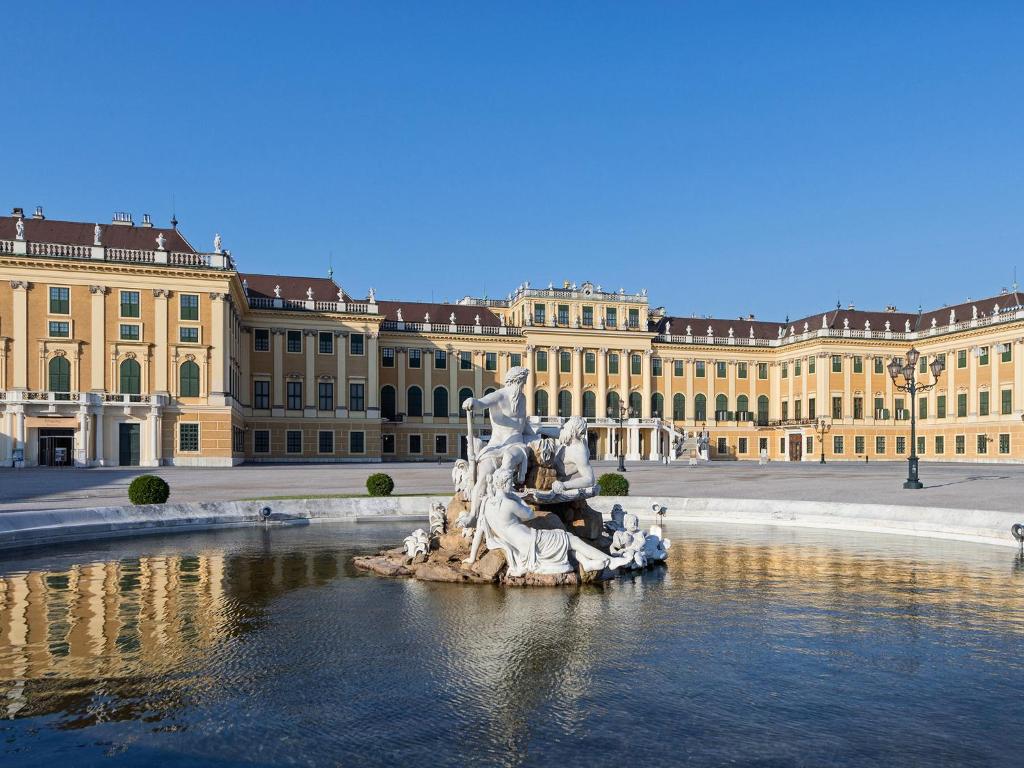 Schloß Schönbrunn Grand Suite في فيينا: تمثال في الماء امام مبنى