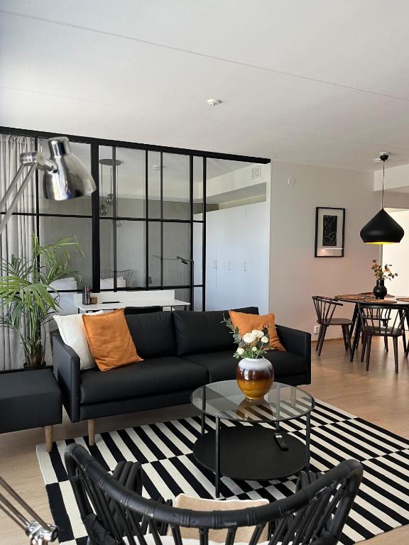 a living room with a black couch and a glass table at Tikka Apartments in Jyväskylä