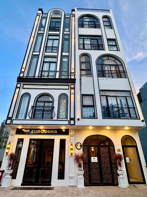 a tall white building with windows on a street at EuroDana Palace Hotel in Danang