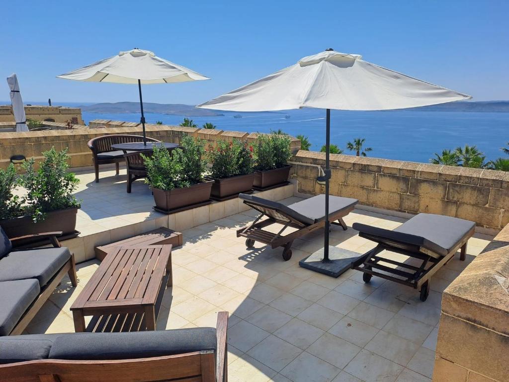 a patio with tables and umbrellas and the ocean at Fort Chambray Island Views in Għajnsielem