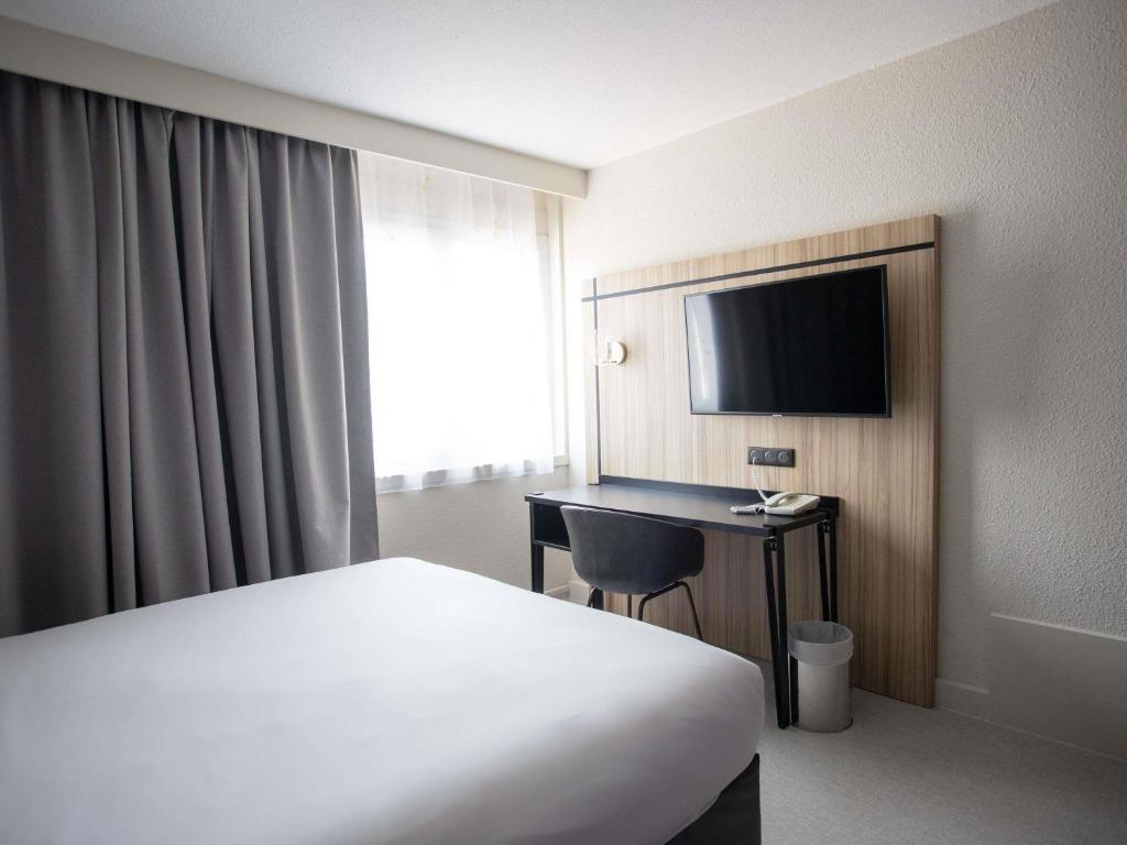 a hotel room with a bed and a desk and a television at ibis Styles Besançon in Besançon
