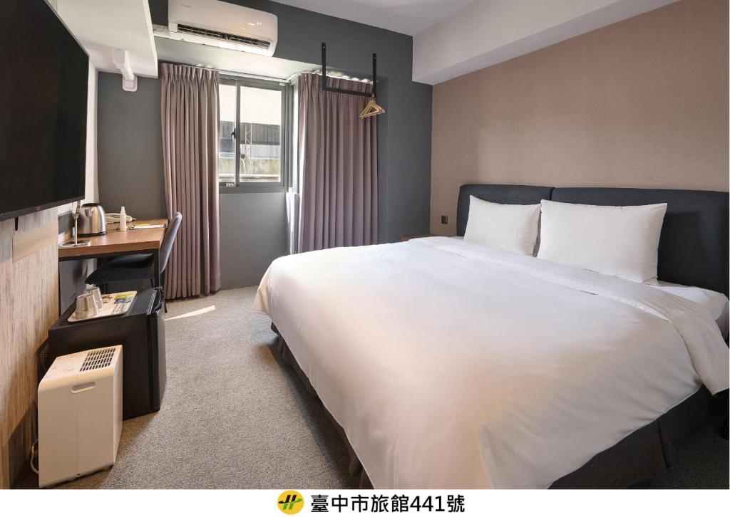 a bedroom with a large white bed and a television at Doudian DDiNN Hotel in Taichung
